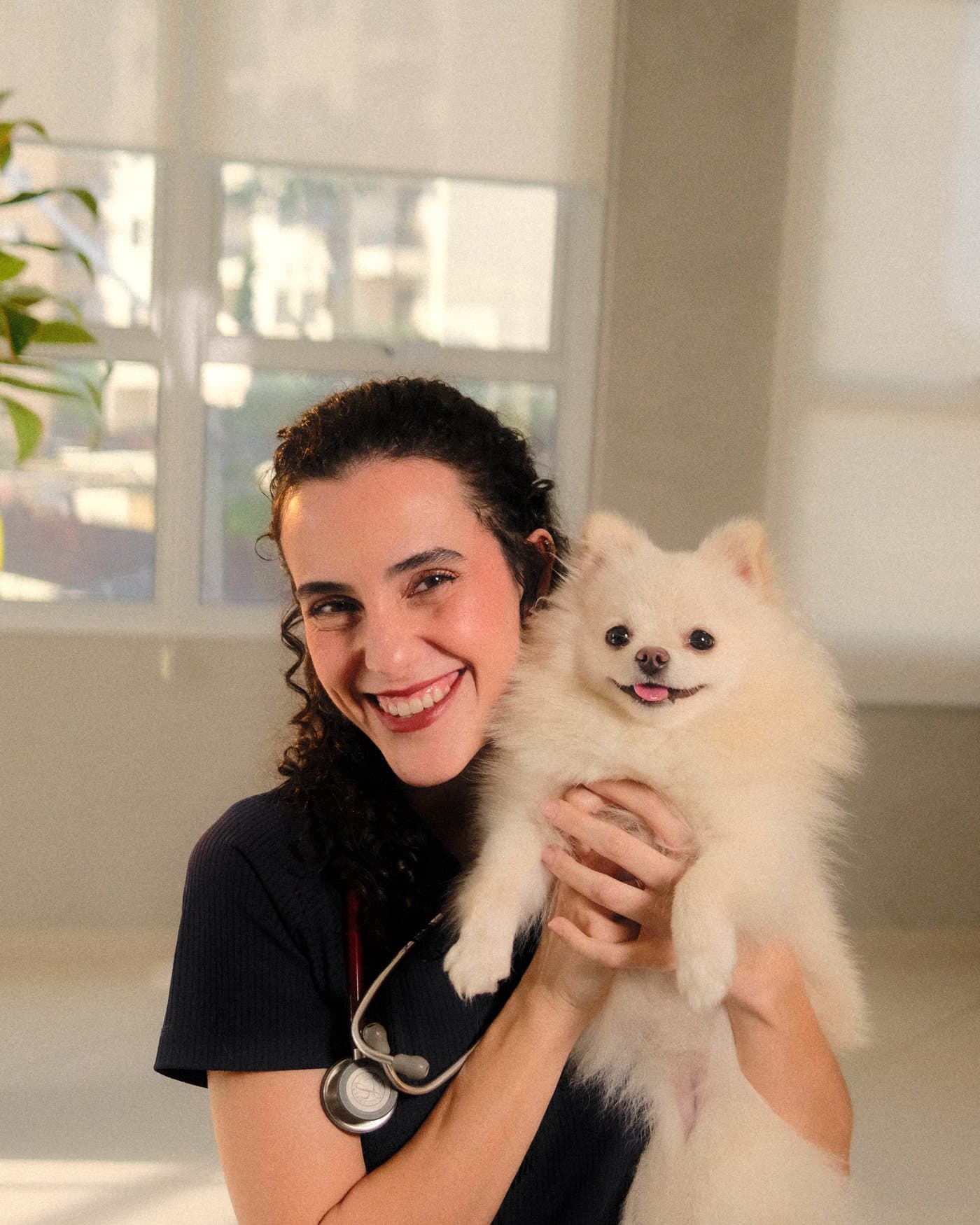 A Dra. Anna Luiza Pollon sorrindo, com um lulu da pomerânia branco no colo.
